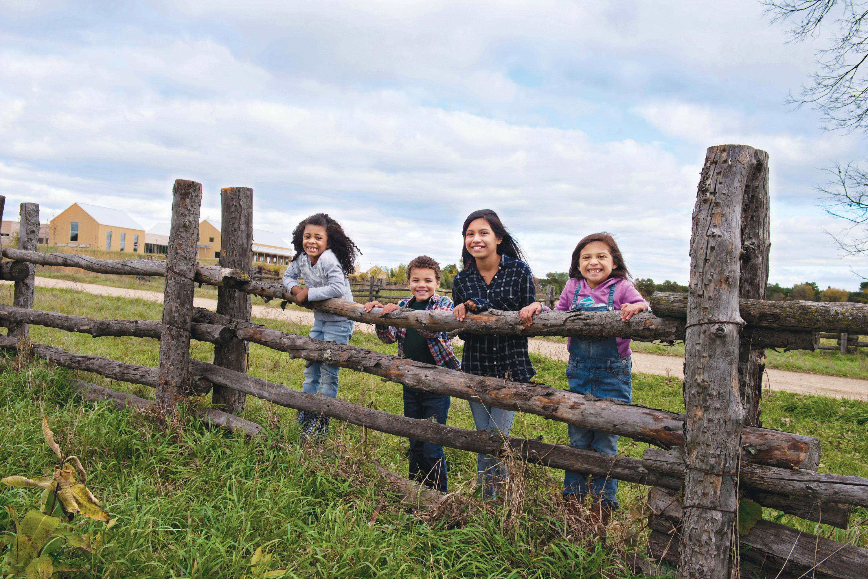 Kids pose on log fence at Oliver Kelley Farm