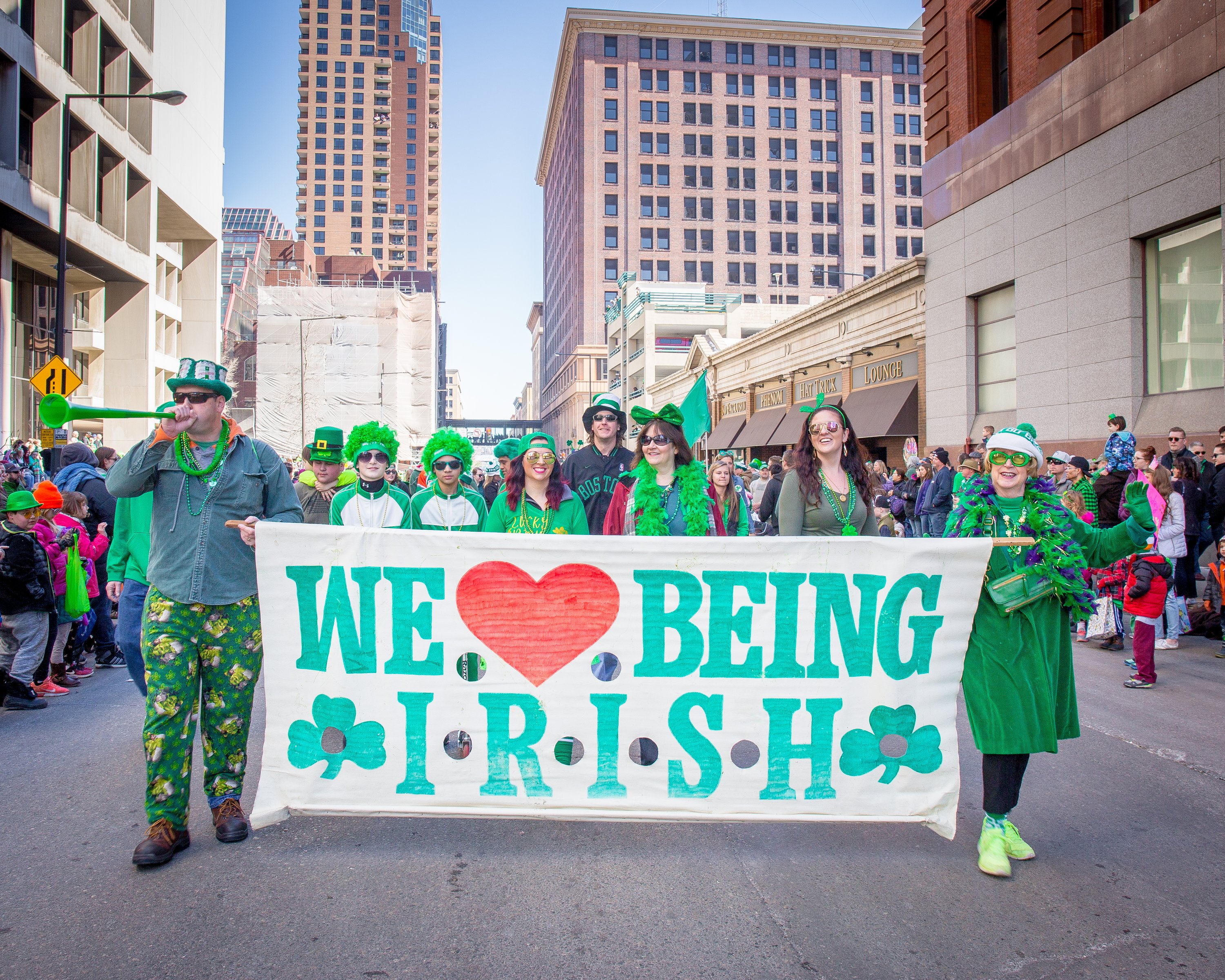 Parade-goers holding a "we love being Irish" banner