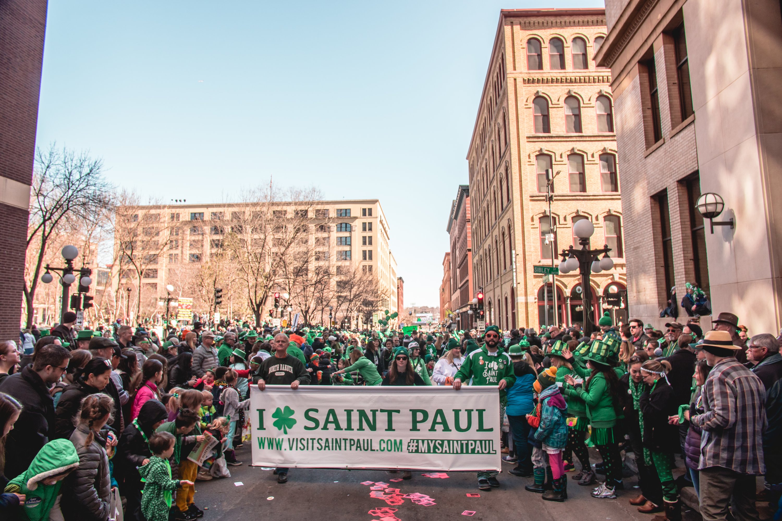 St. Patrick's Day parade-goers holding a Visit Saint Paul banner