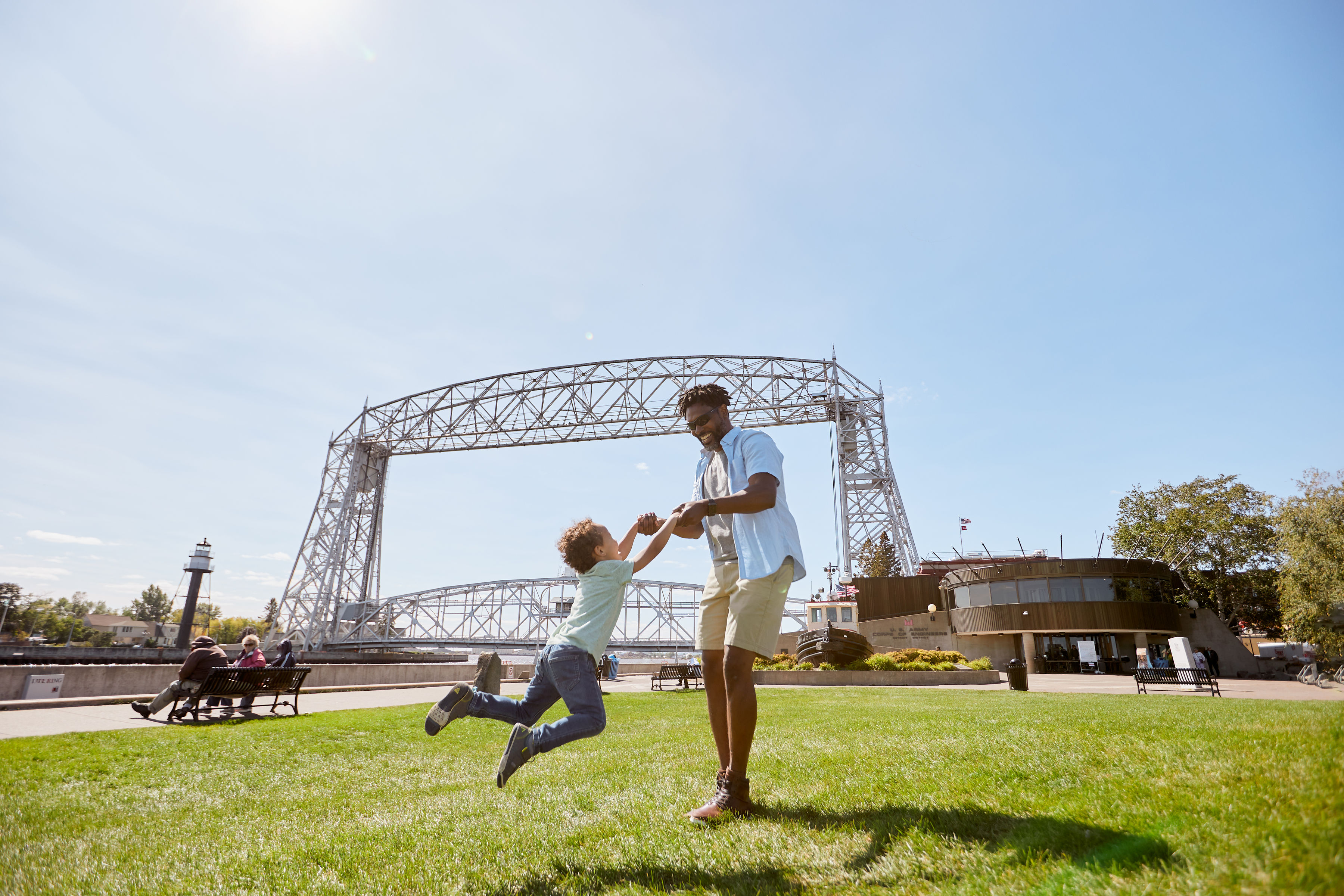 Father playfully spins his son around by the arms in front of the Duluth lift bridge