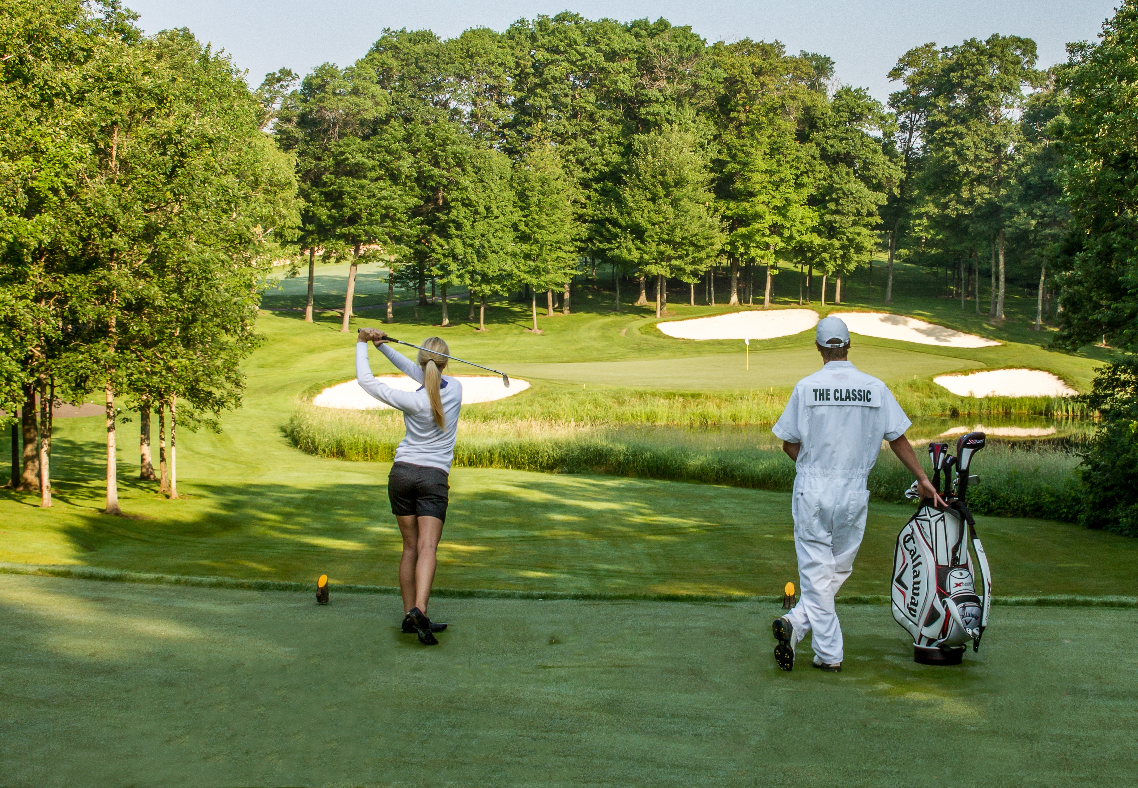 Woman golfing at The Classic at Madden's Resort while caddy holds her clubs