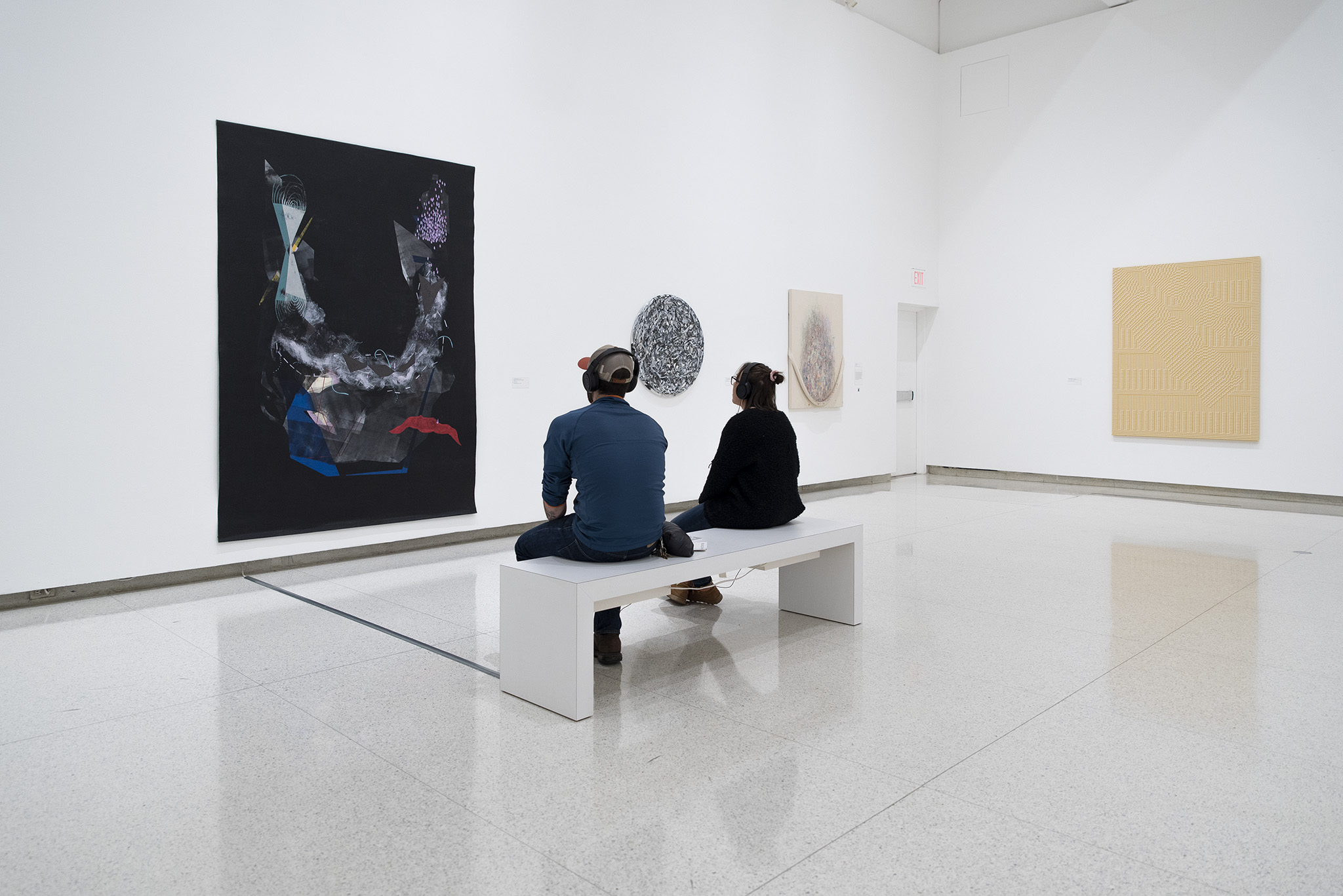 Two people sitting on a bench to view a painting at the Walker Art Center