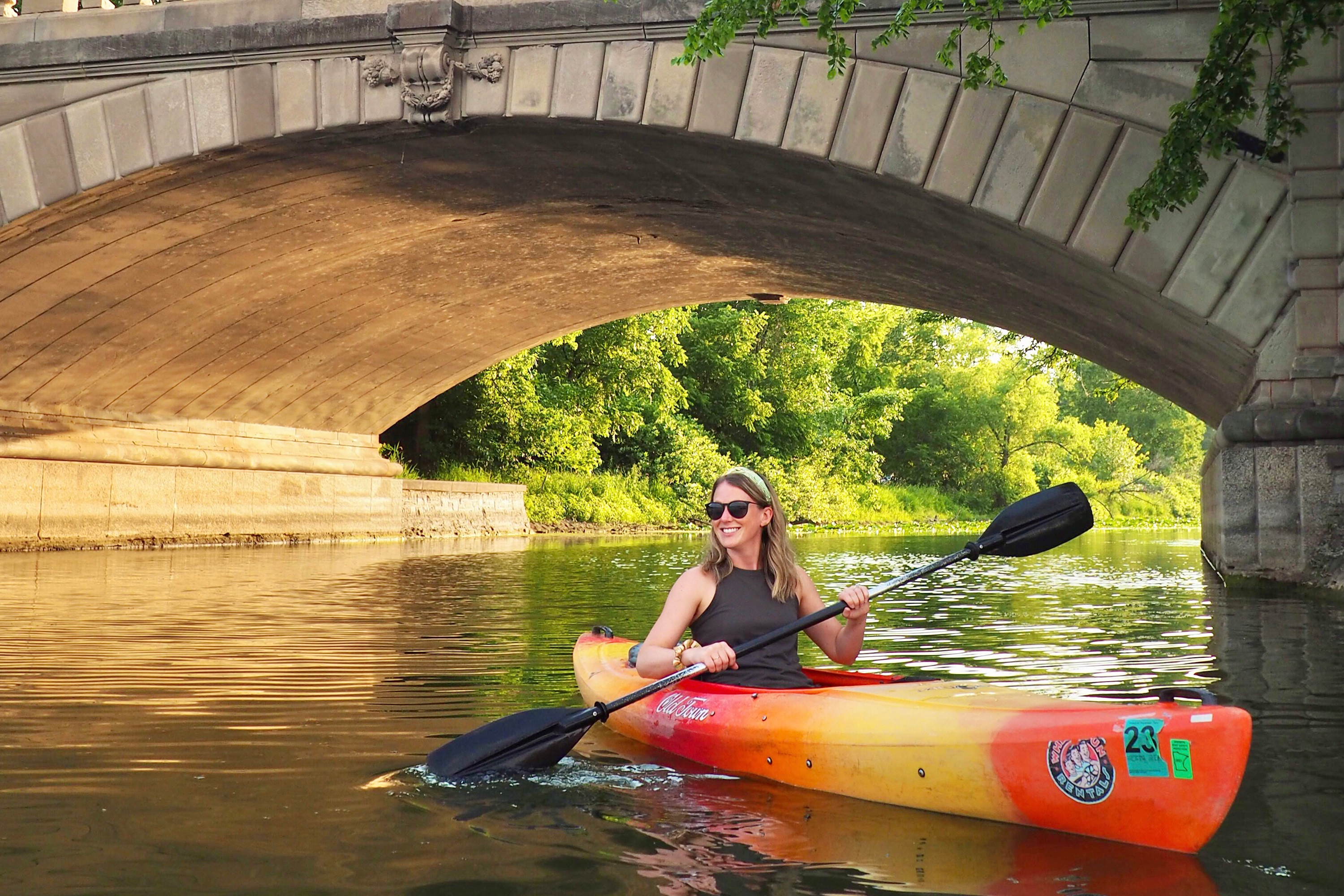 Sara kayaking near a small bridge