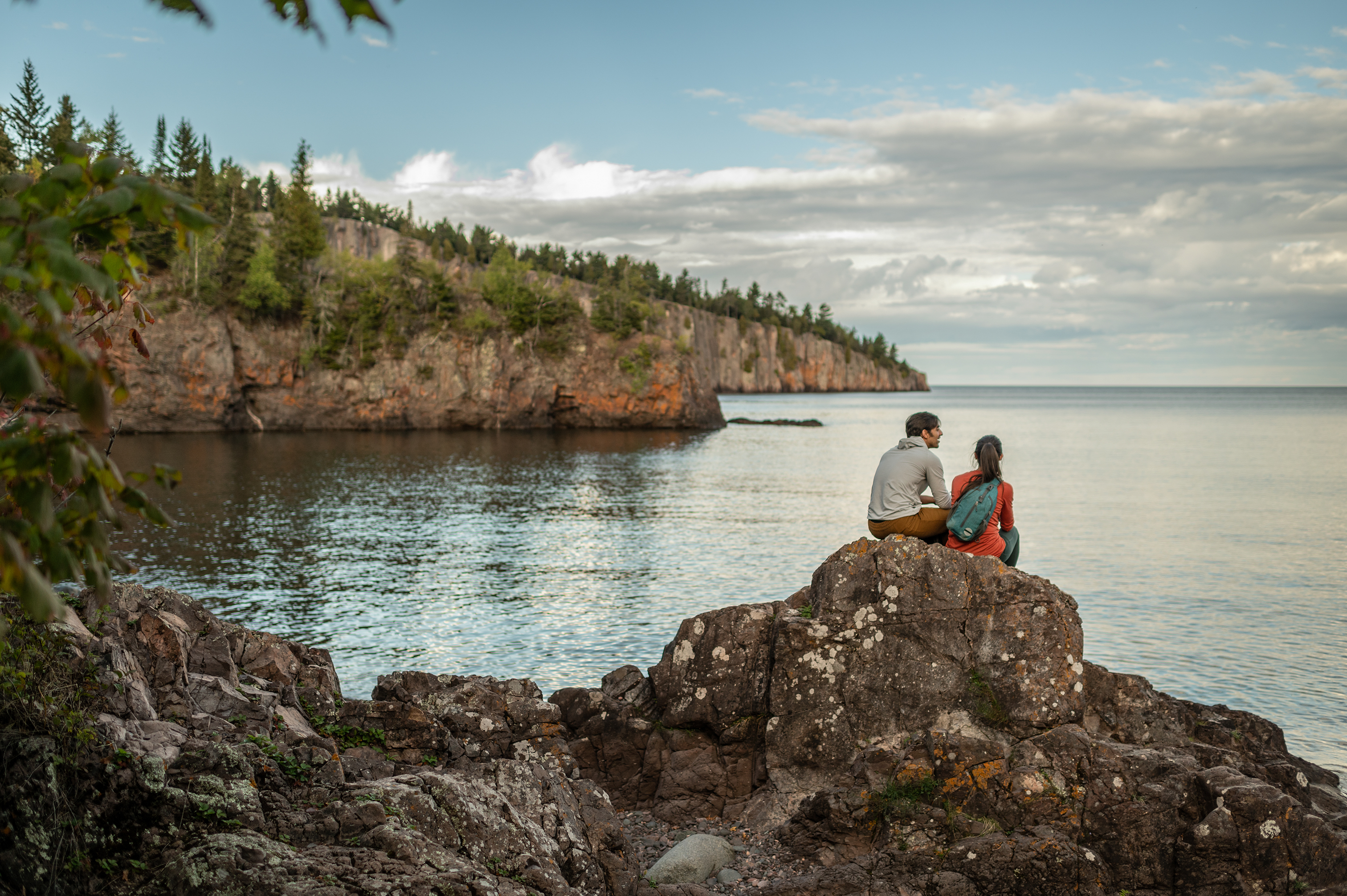 A pair of hikers sit on a rock overlooking Silver Bay in Tettegouche State Park