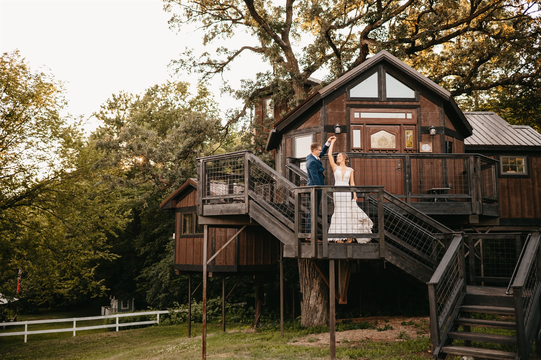 A married couple poses in front of the treehouse suite at Hope Glen Farm