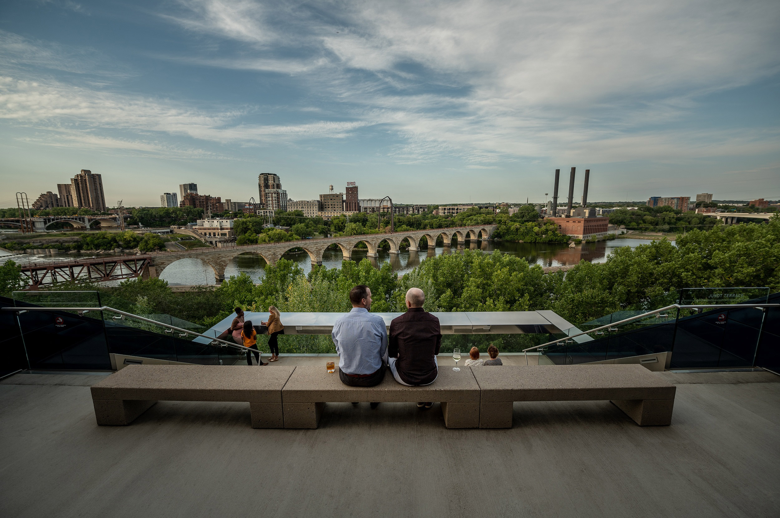 A couple men look at the Minneapolis skyline from the top of the Guthrie Theater