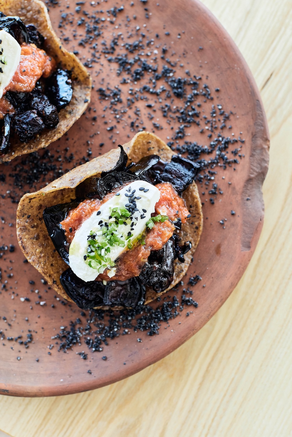 Charred eggplant tostadas with roasted tomato, sesame, lime and burrata at Colita