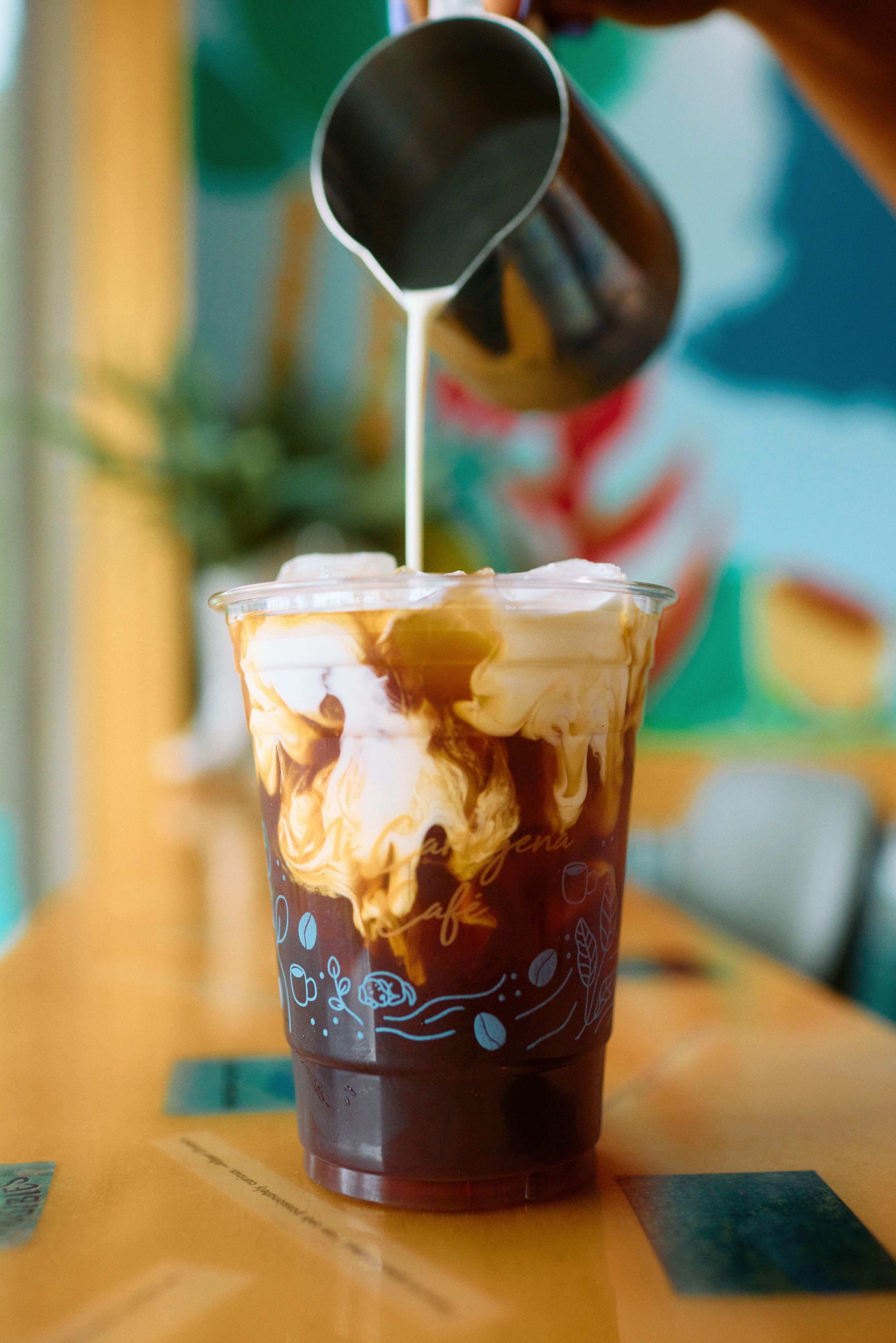 A barista pours milk into an iced latte at Mi Cartagena Coffee