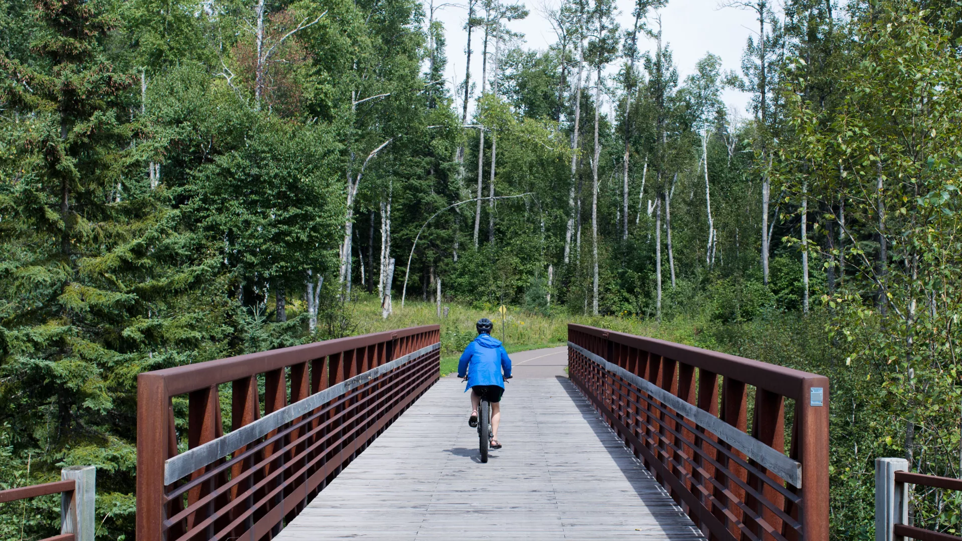 Bicyclist rides across a bridge on the Gitchi-Gami State Trail