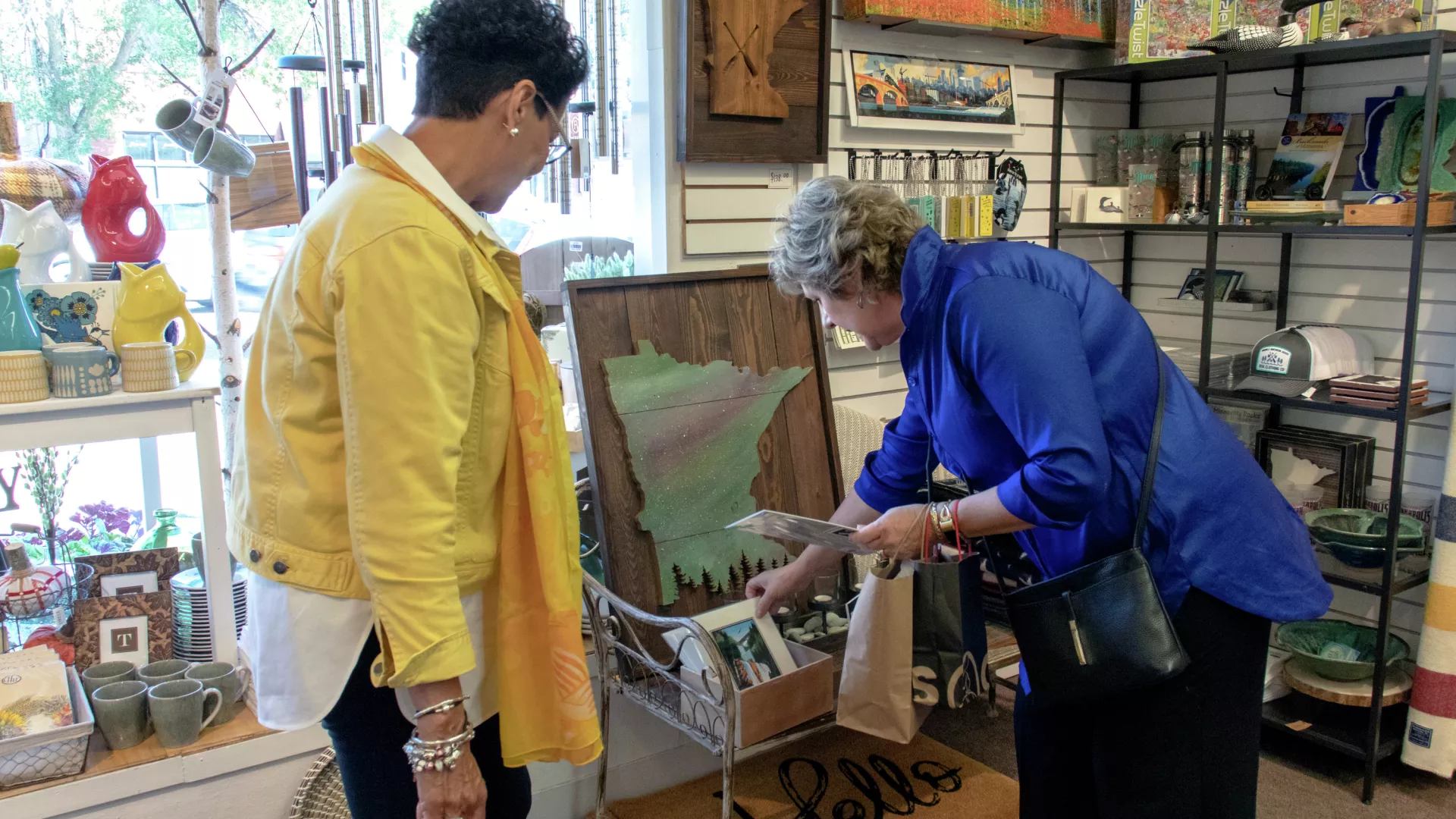 Women look at Minnesota-shaped gifts
