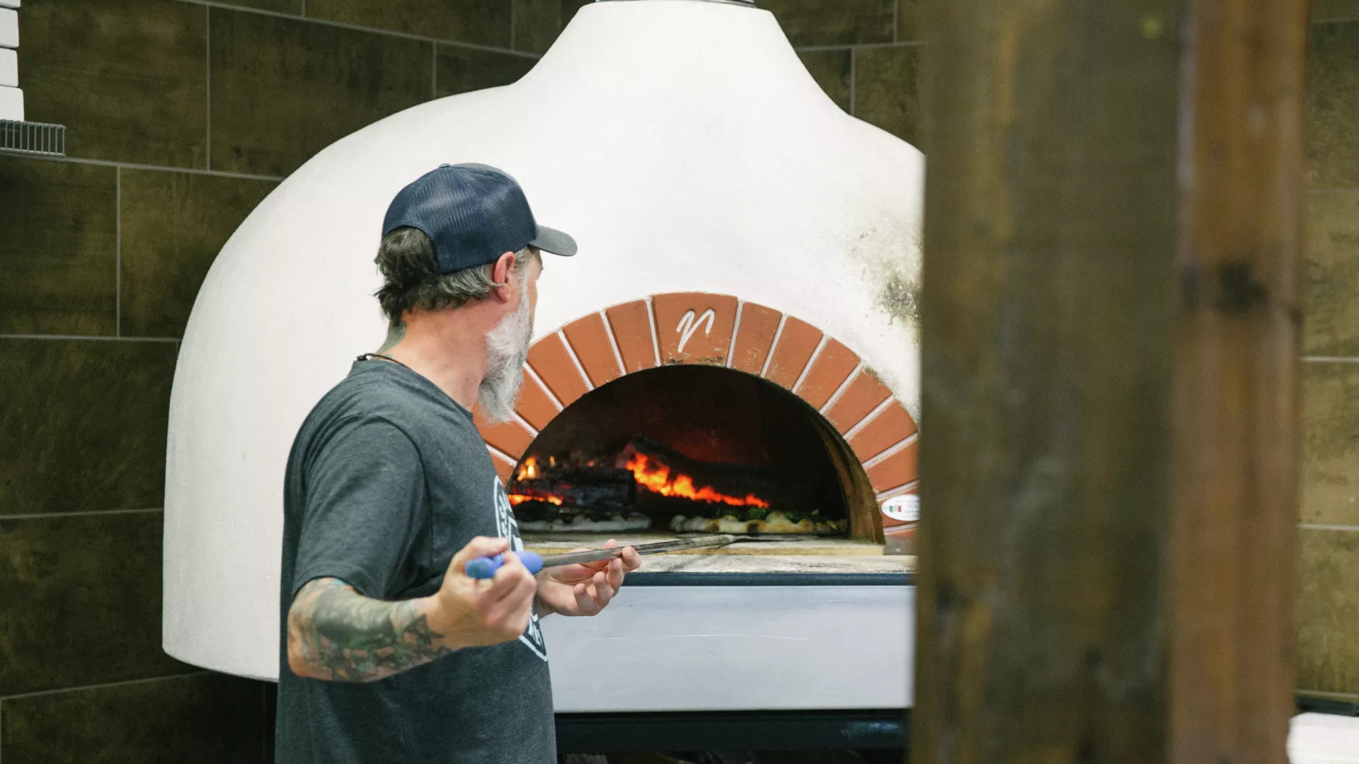 Man tends wood-fired pizza oven