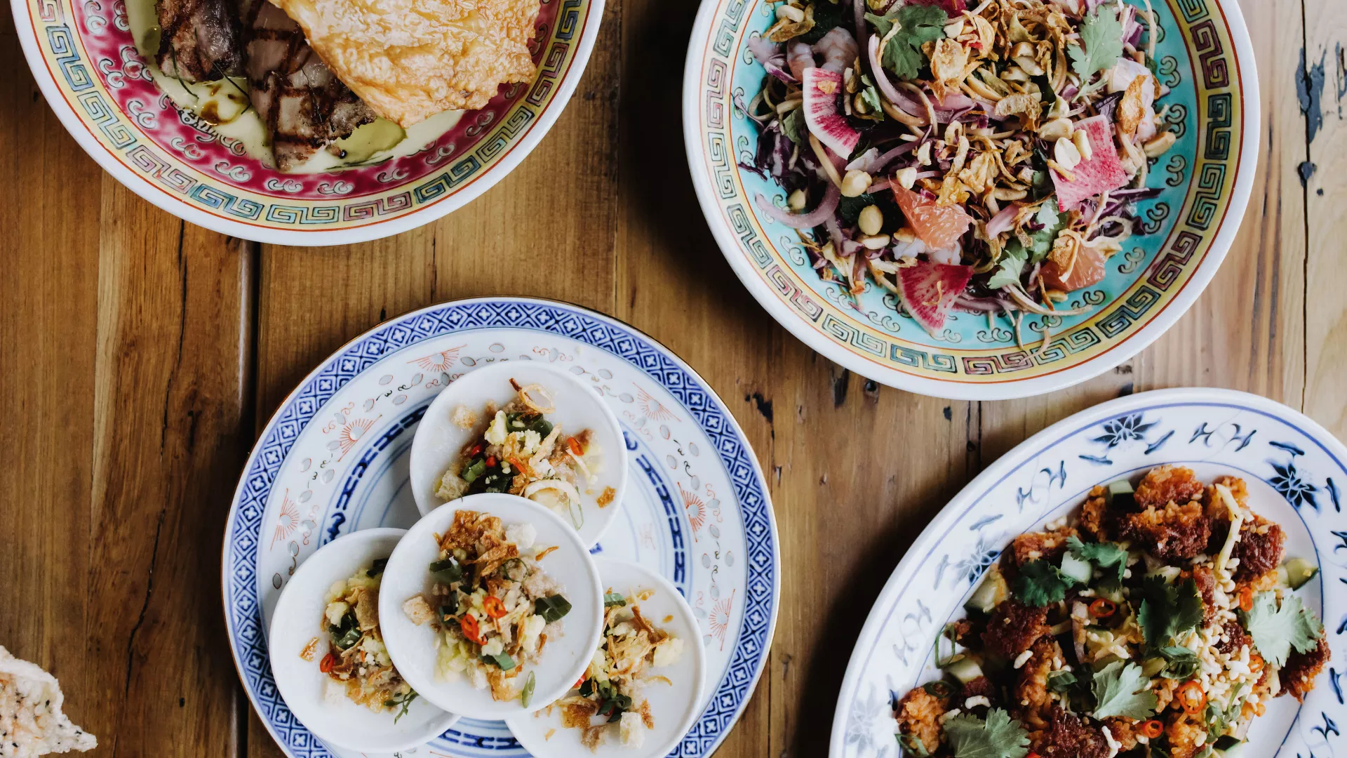 Minneapolis restaurant serves four plates of Vietnamese food on a wooden table