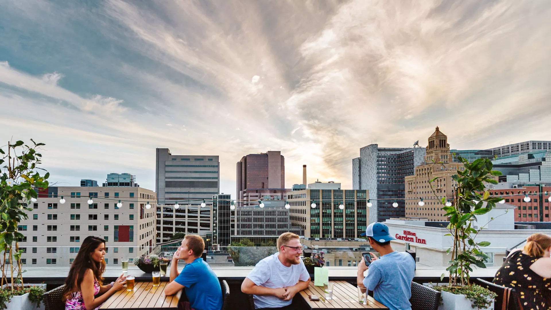 Diners on a rooftop patio overlooking downtown Rochester