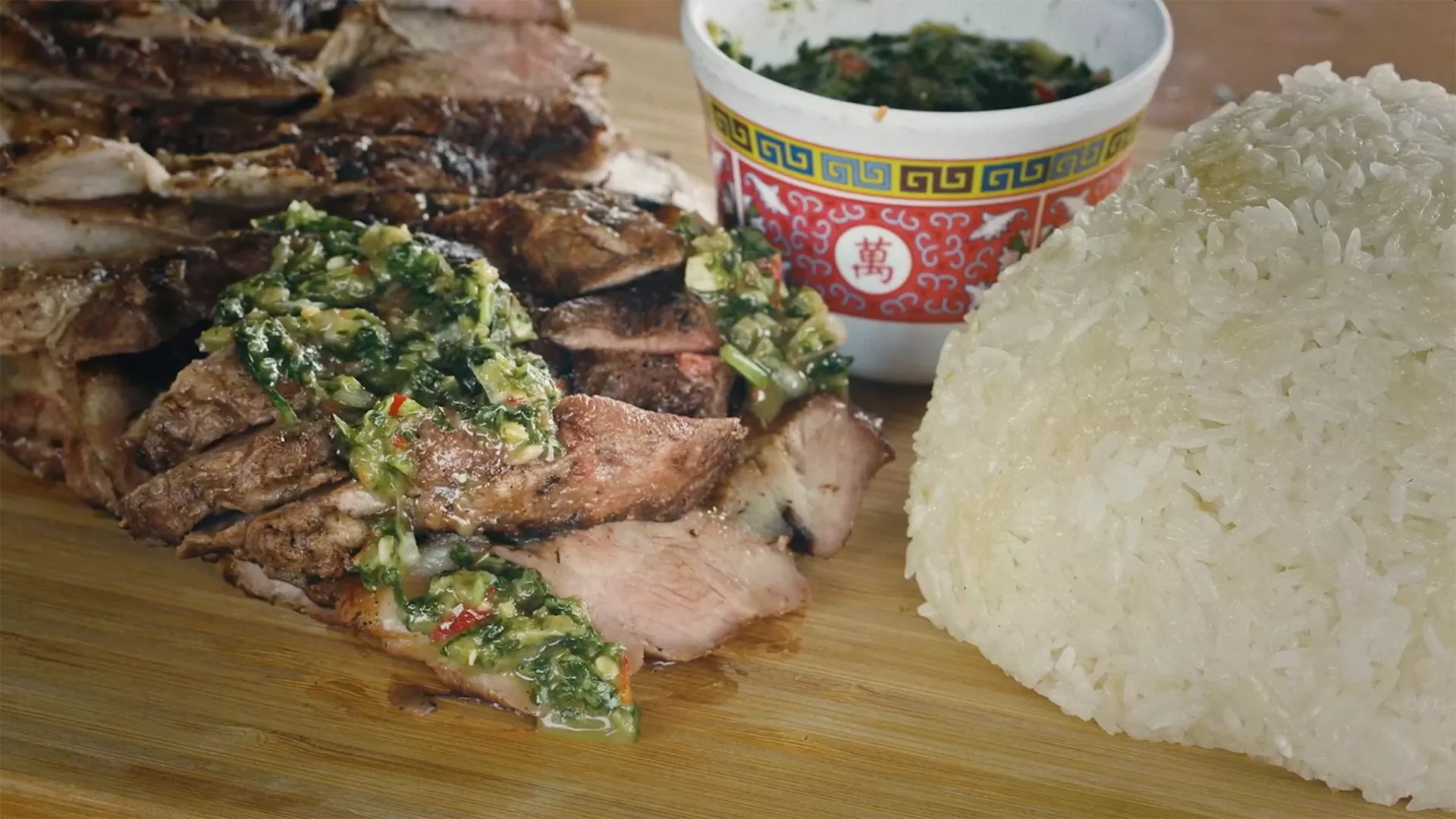 Sliced pork coppa dressed with a finely chopped sauce, accompanied by a mound of sticky rice