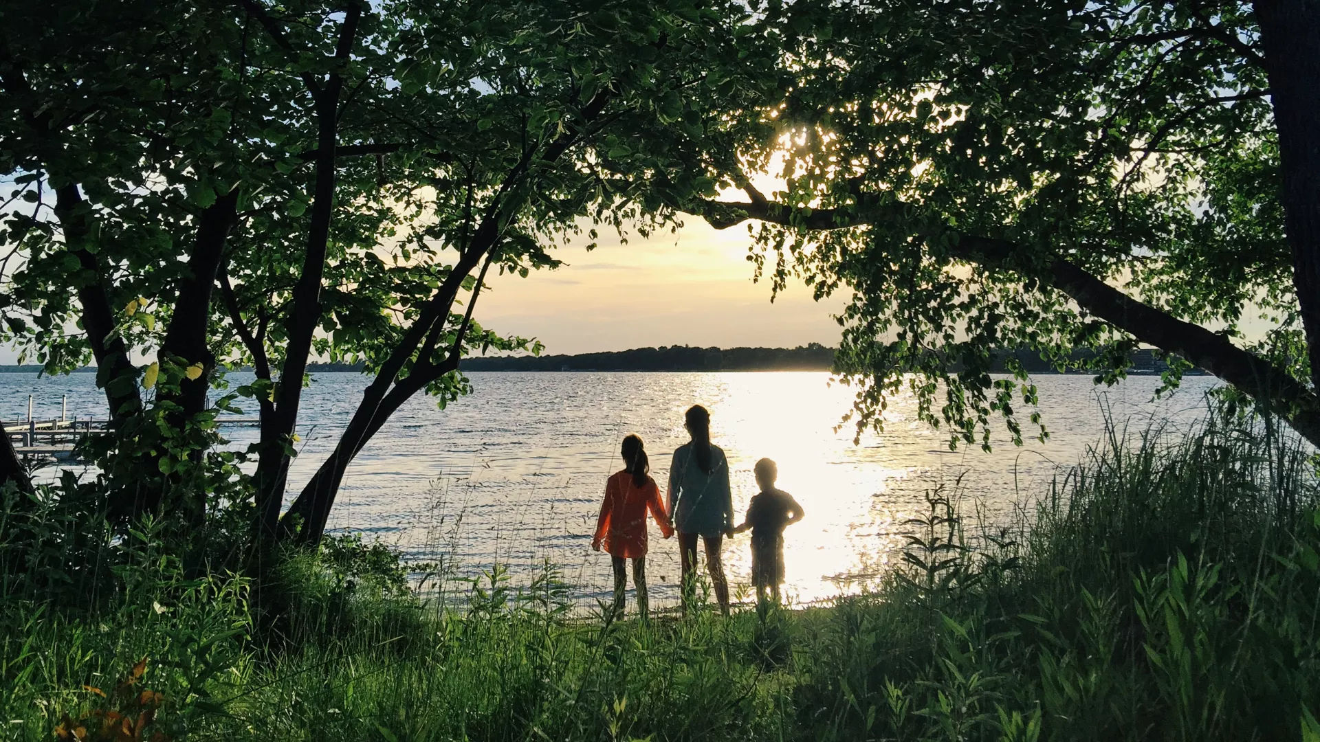 Three children looking out over the water at sunset