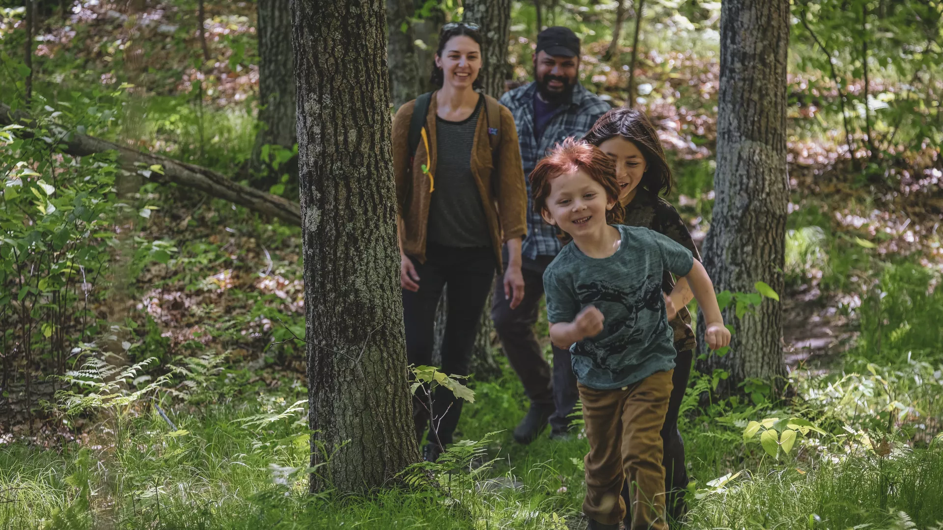 family hiking through the woods single file