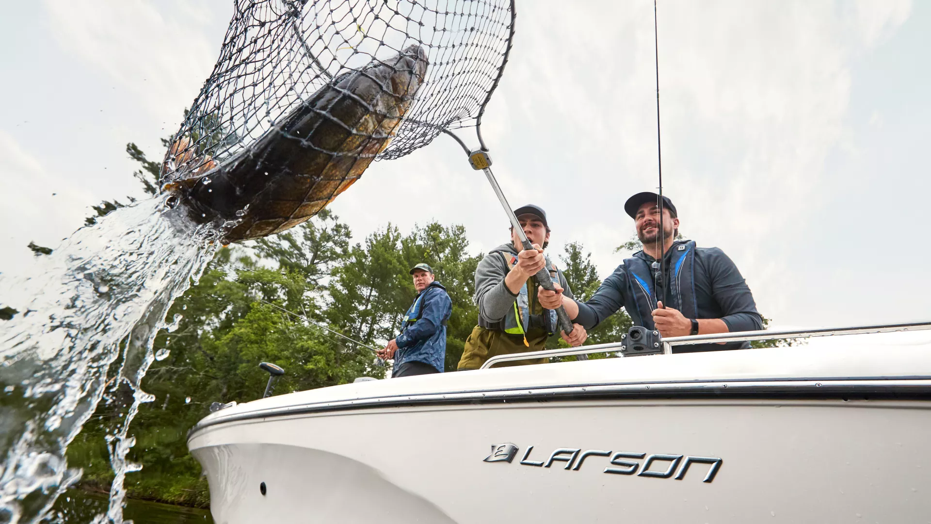 Catching a large fish in a net off the side of a boat