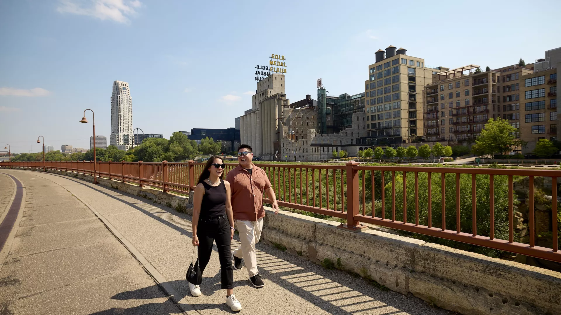 Two friends walk across the Stone Arch Bridge in Minneapolis