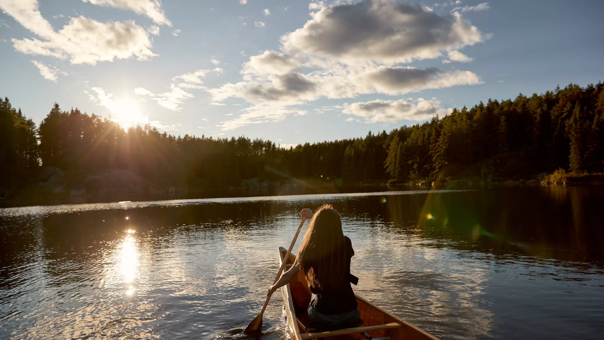 A woman canoeing in the Boundary Waters as the sun goes down