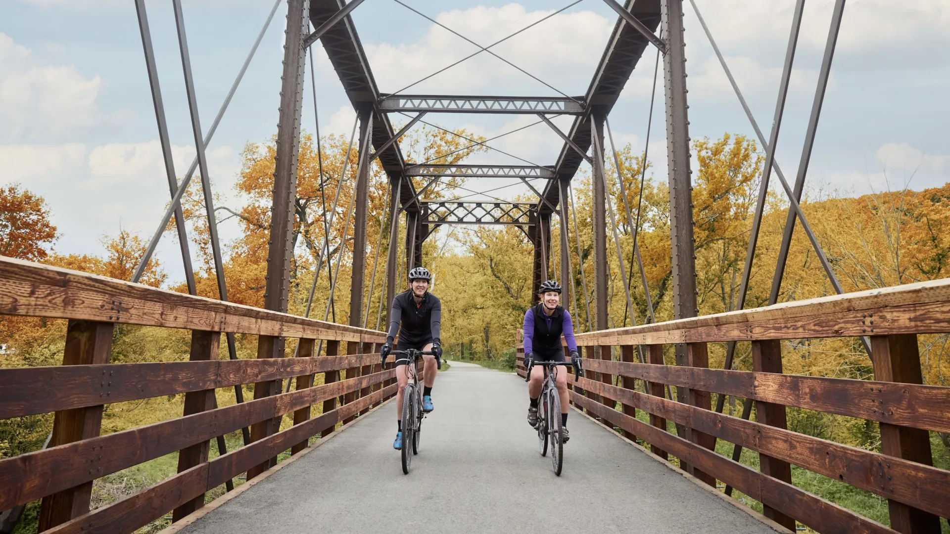 A couple bikers along a bridge in Lanesboro during fall