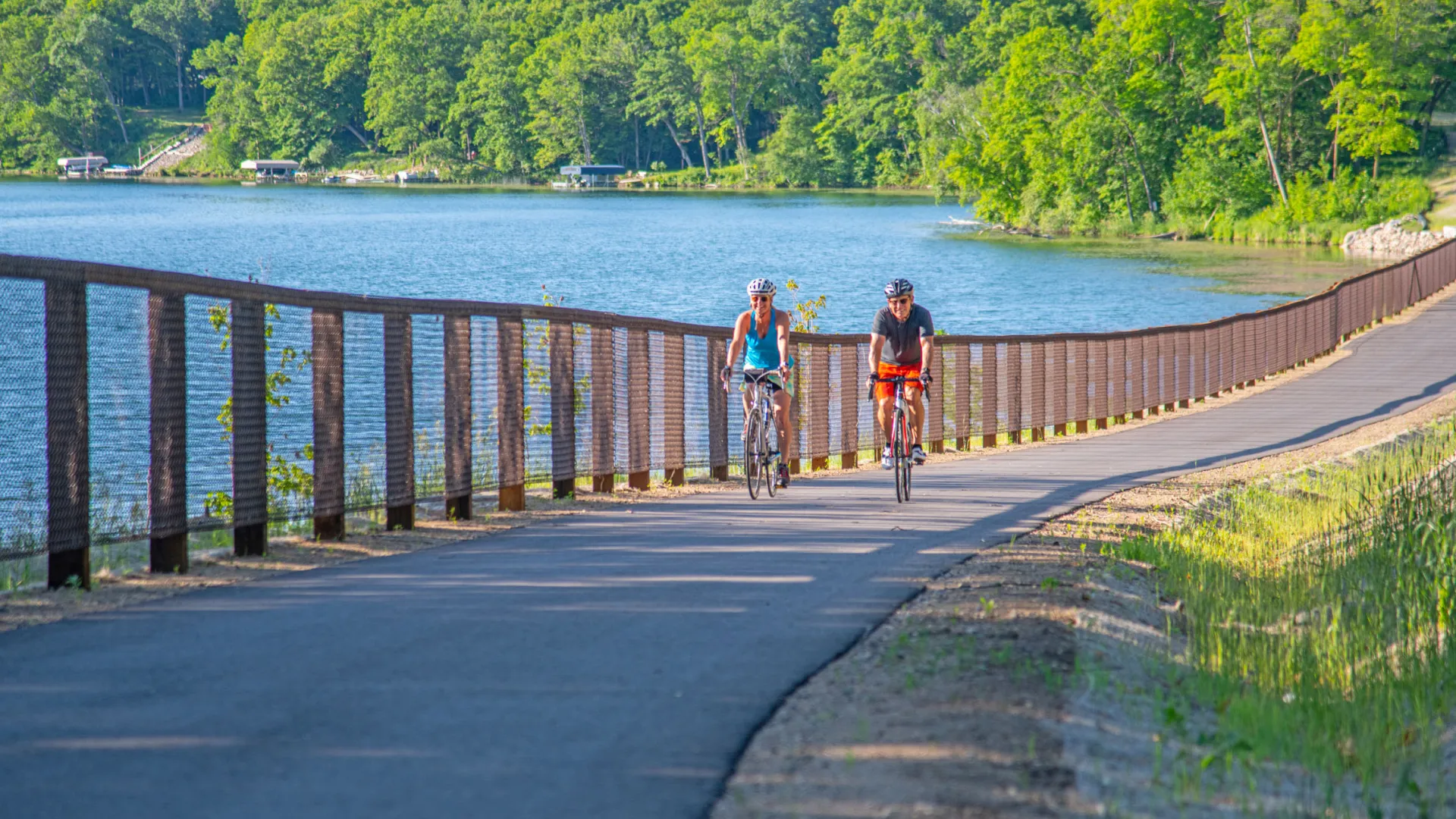 A couple bikers pass Acorn Lake on the Heartland State Trail