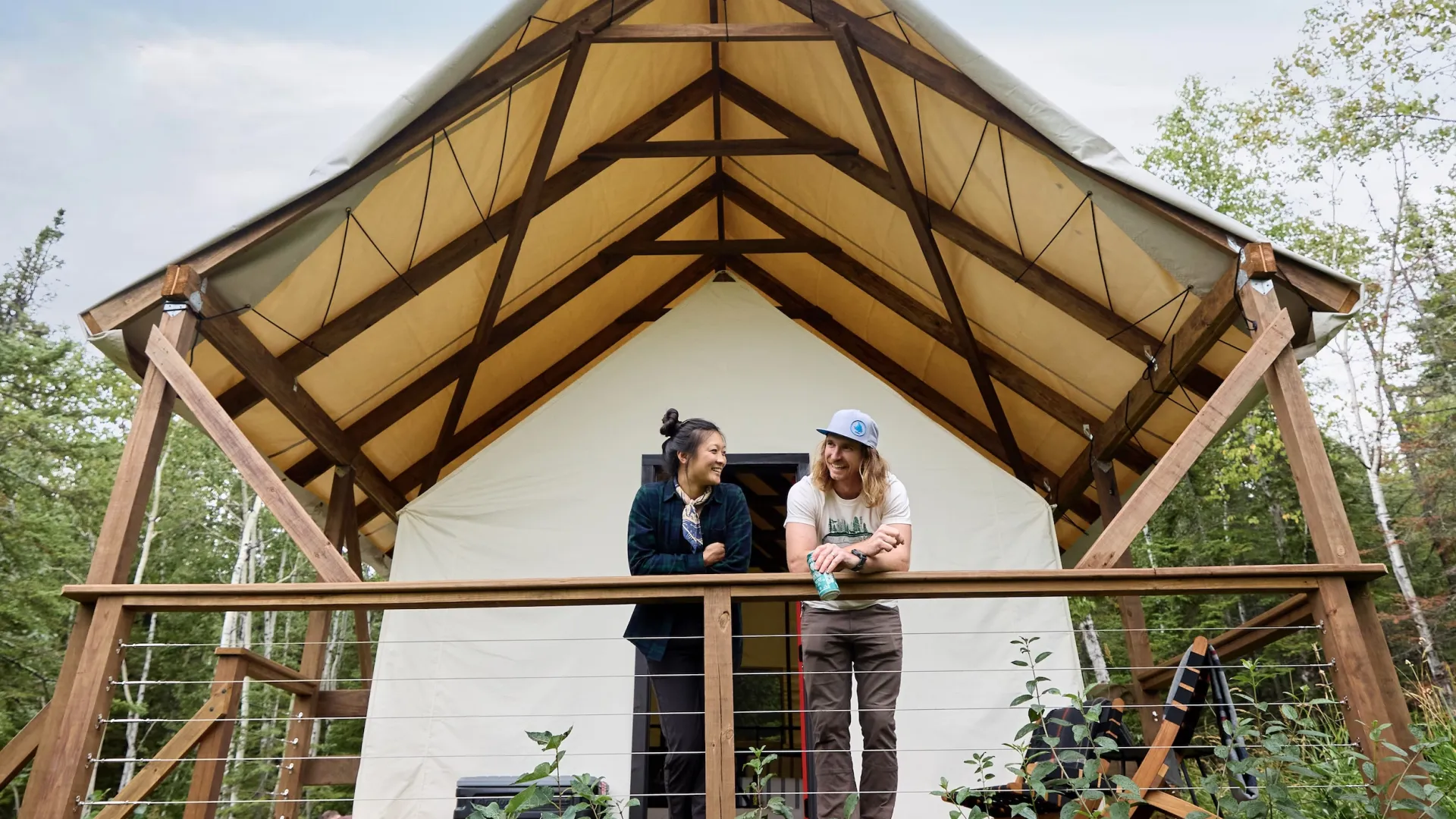 A couple looks out from their canvas tent at North Shore Camping Co