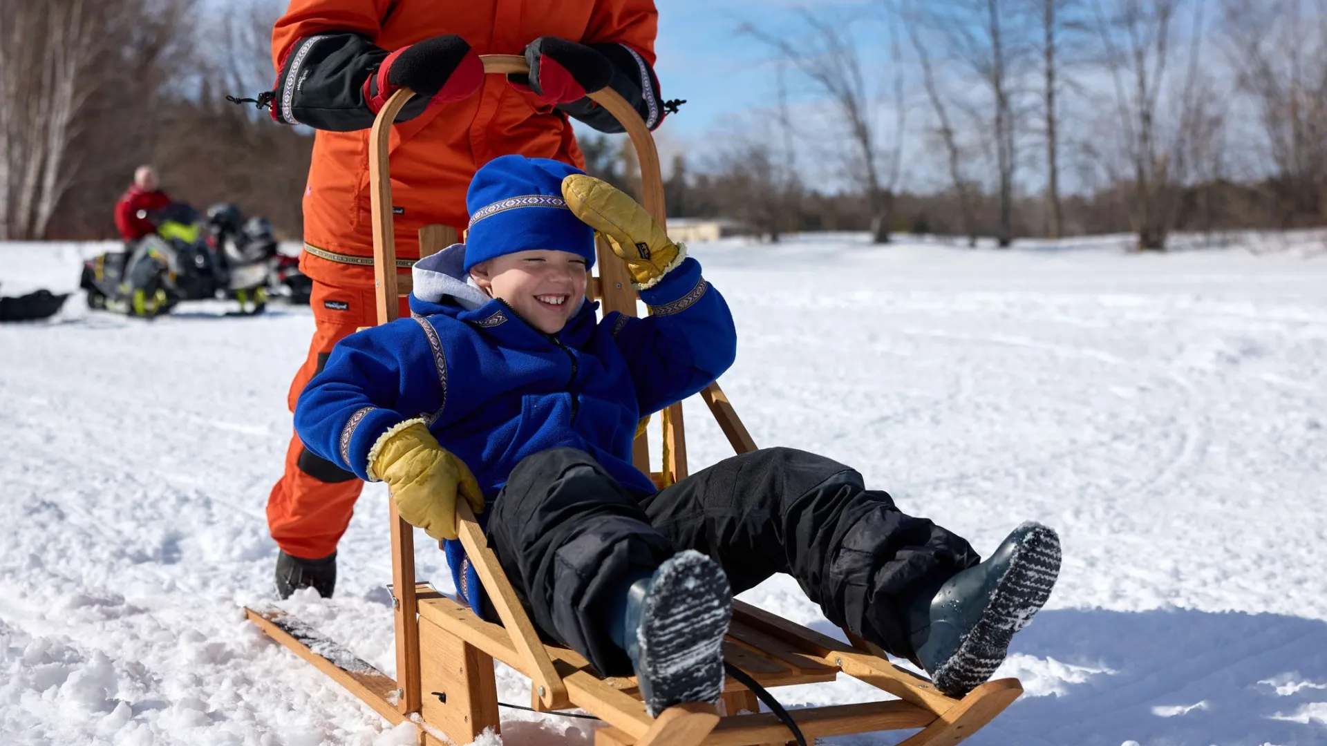 A child gets pulled along snow with a sled from Northern Toboggan Co