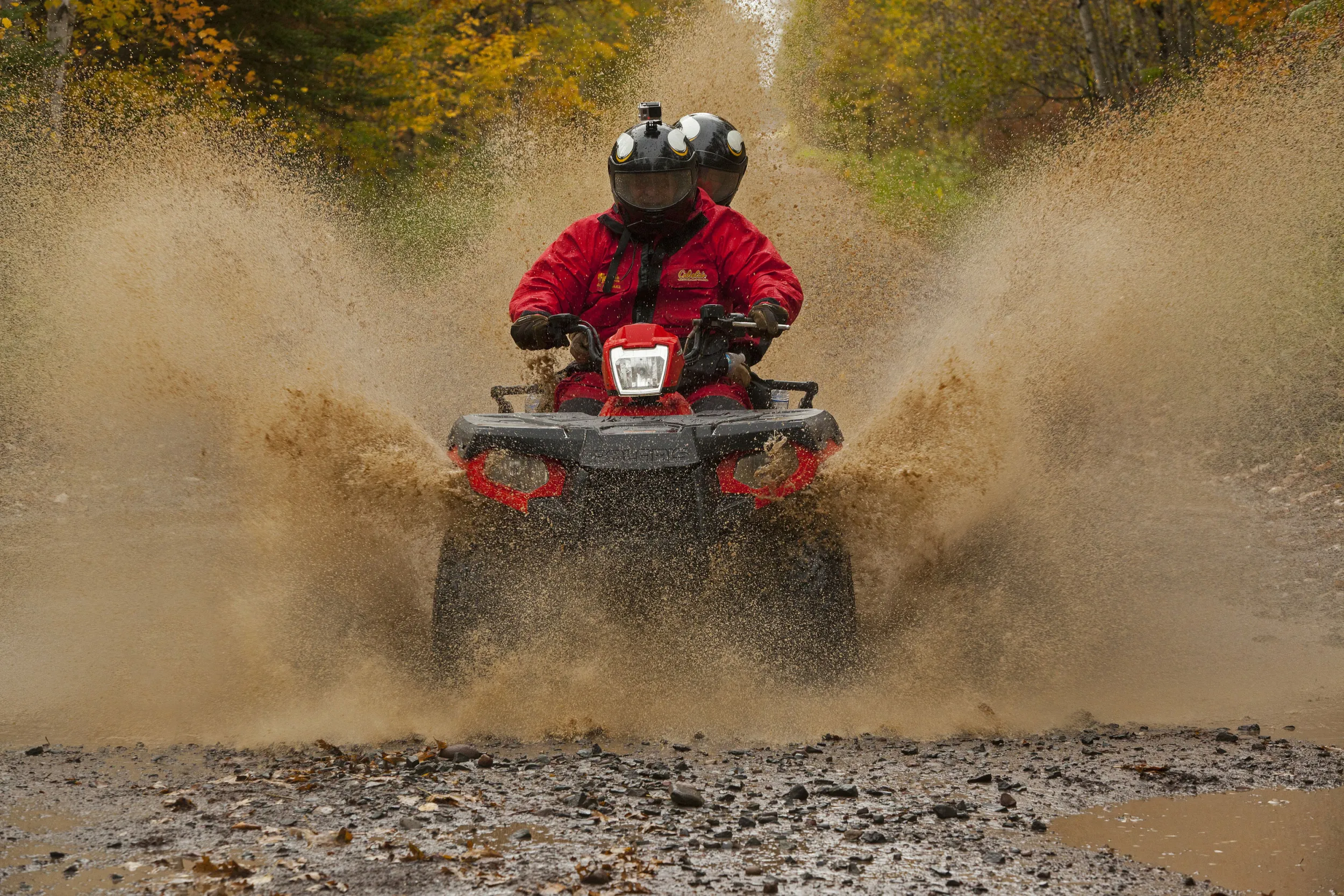 ATV riders go through a mud puddle