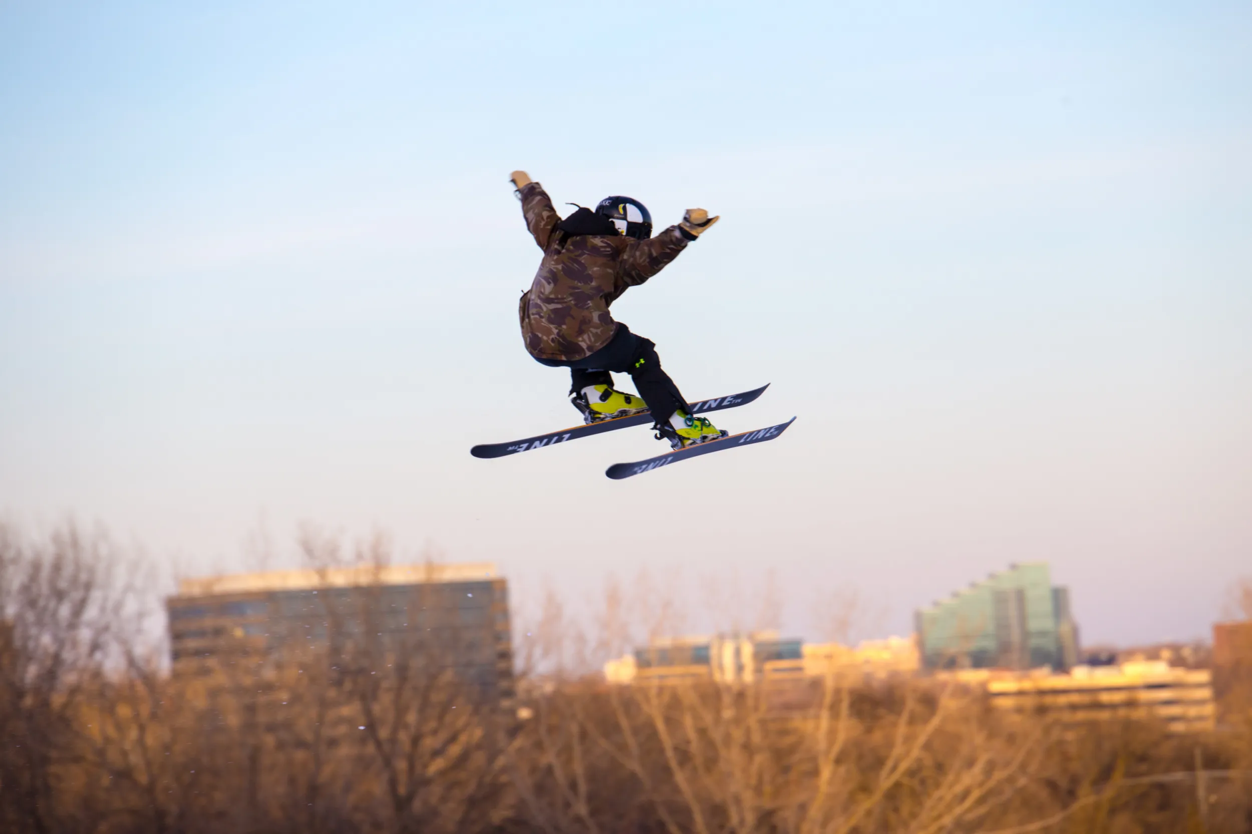 Skier jumping with buildings behind at Hyland Hills