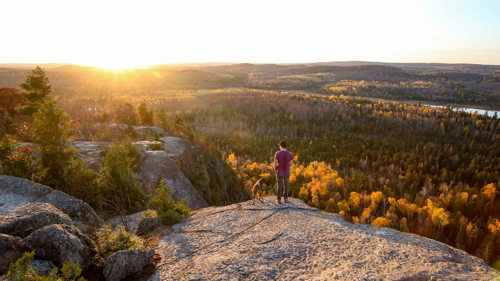 Man watching sunset with his dog on Minnesota's Superior Hiking Trail