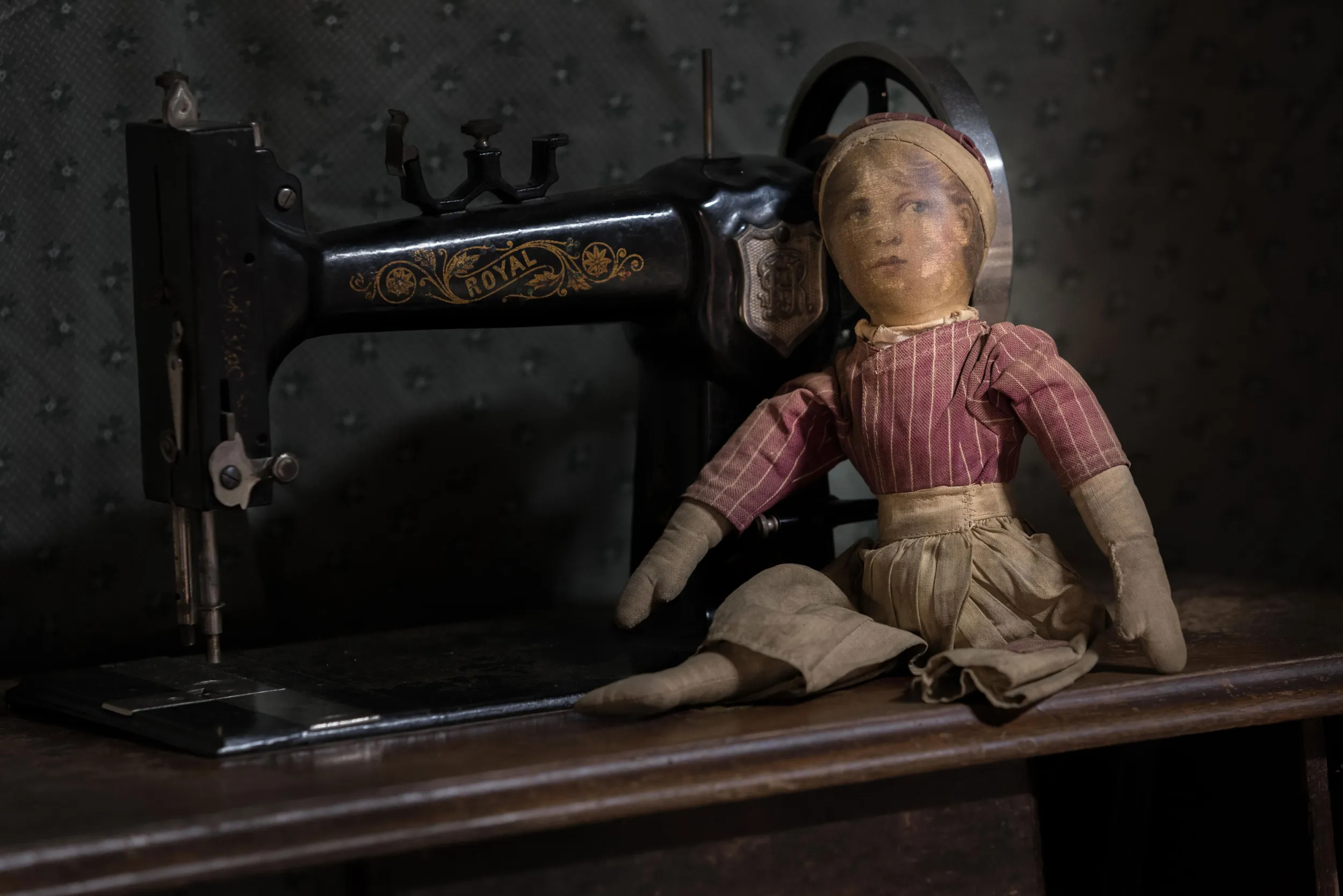 Creepy doll beside a vintage sewing machine