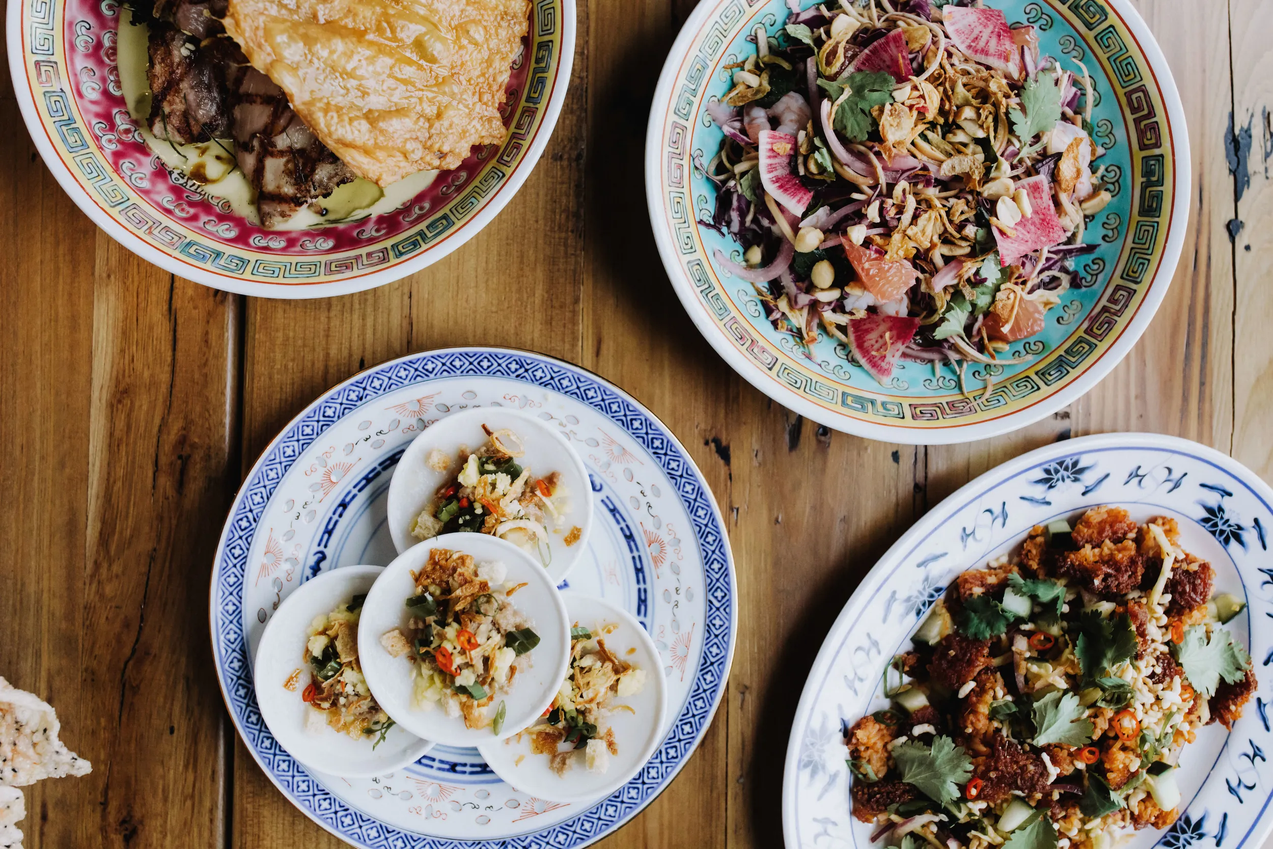 Minneapolis restaurant serves four plates of Vietnamese food on a wooden table