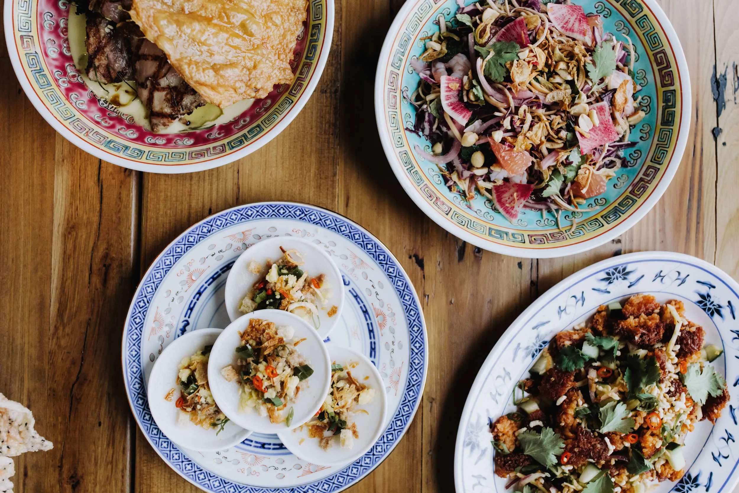 Minneapolis restaurant serves four plates of Vietnamese food on a wooden table