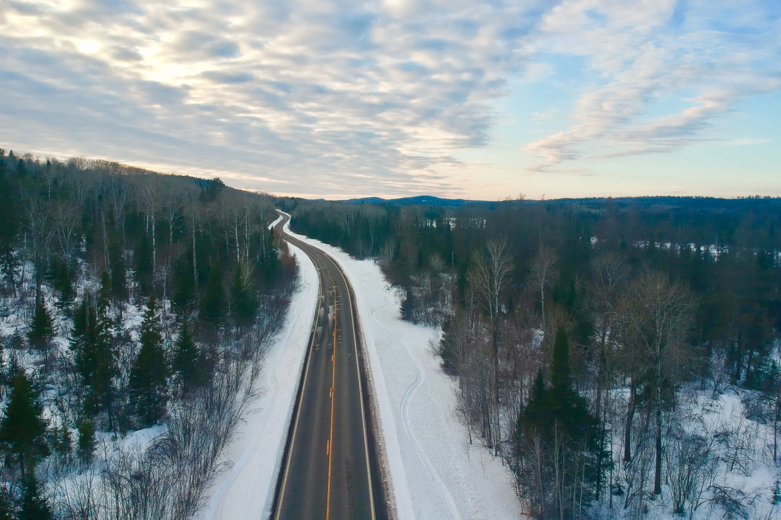 Winding road cuts through the a wintery forest scene