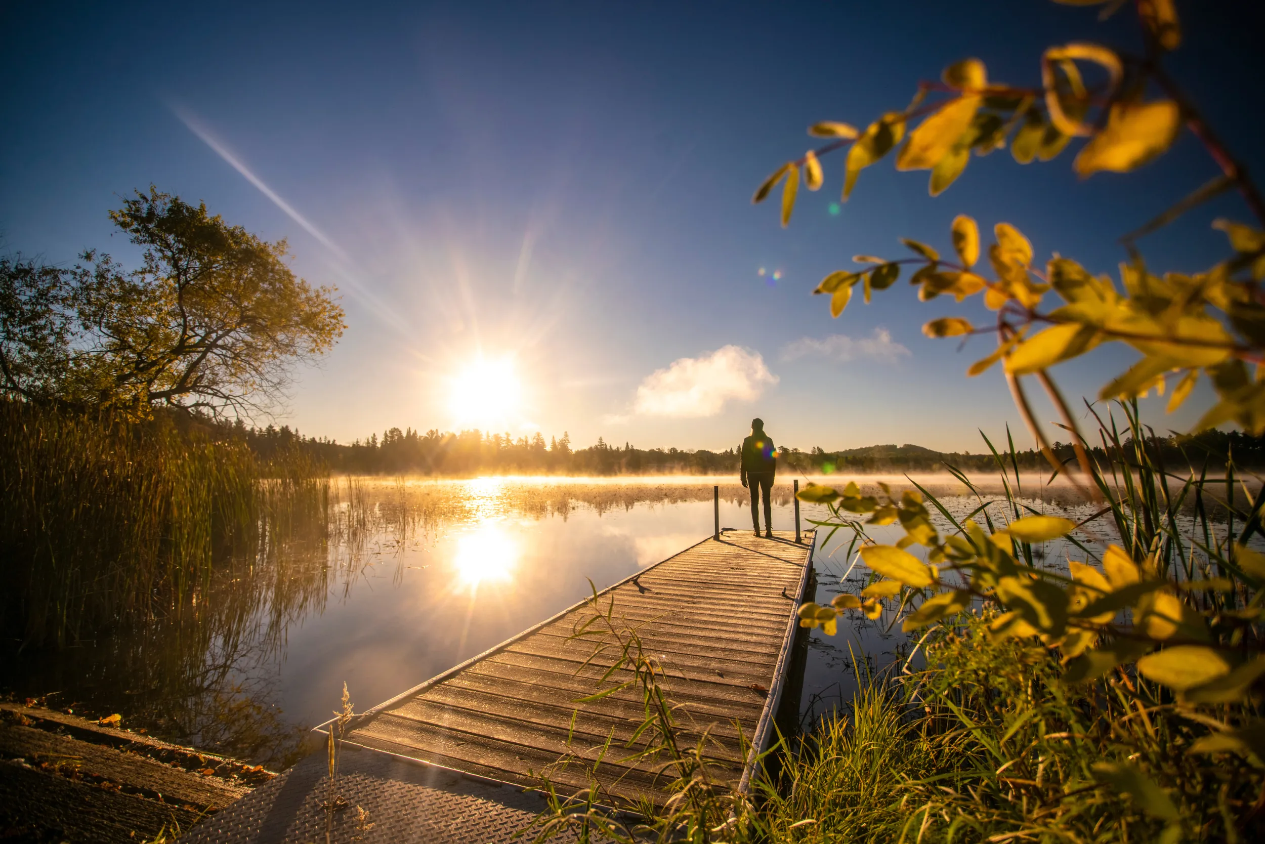Man standing on the end of a dock, overlooking a lake in central Minnesota
