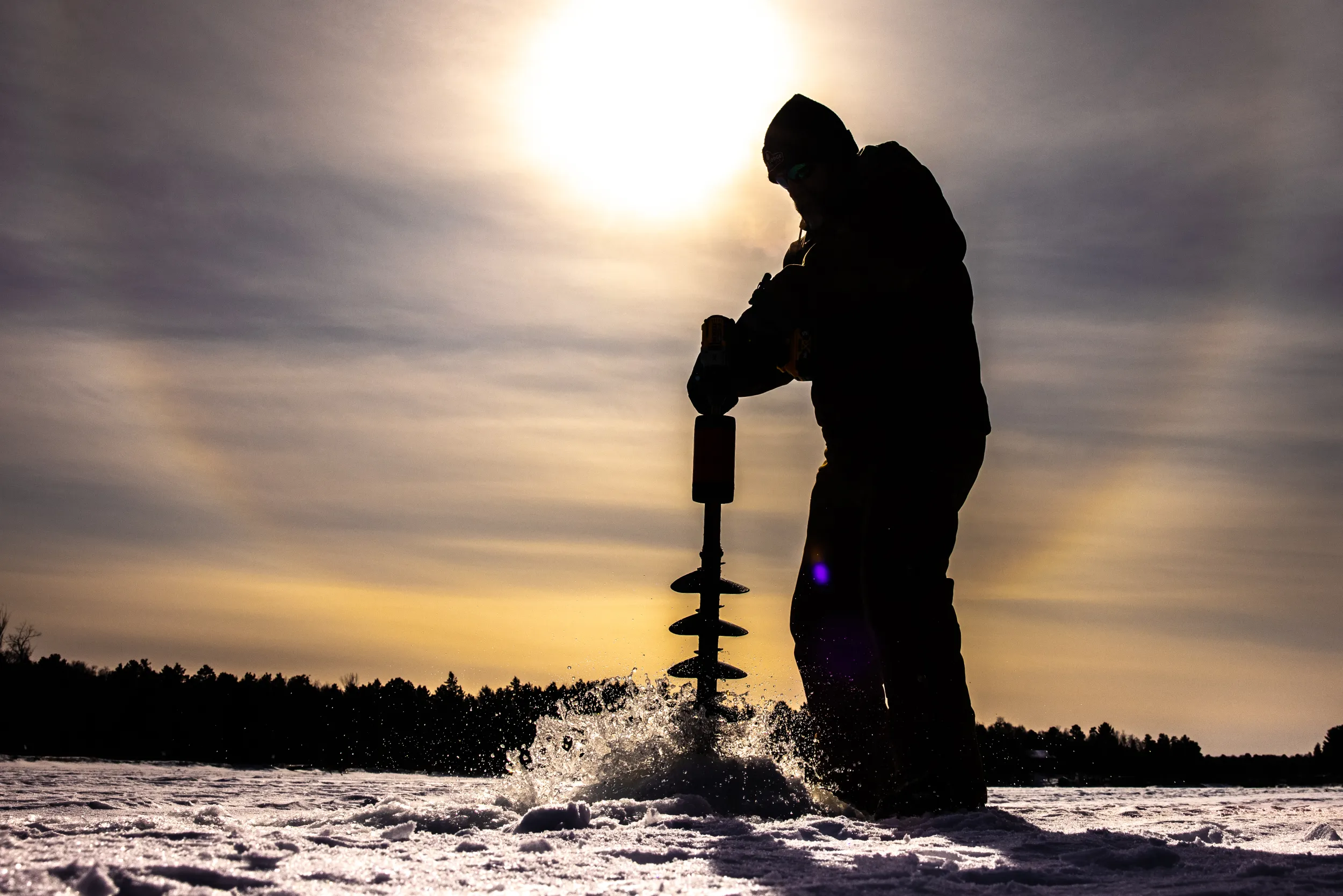 Drilling a hole for ice fishing on Whitefish Lake 