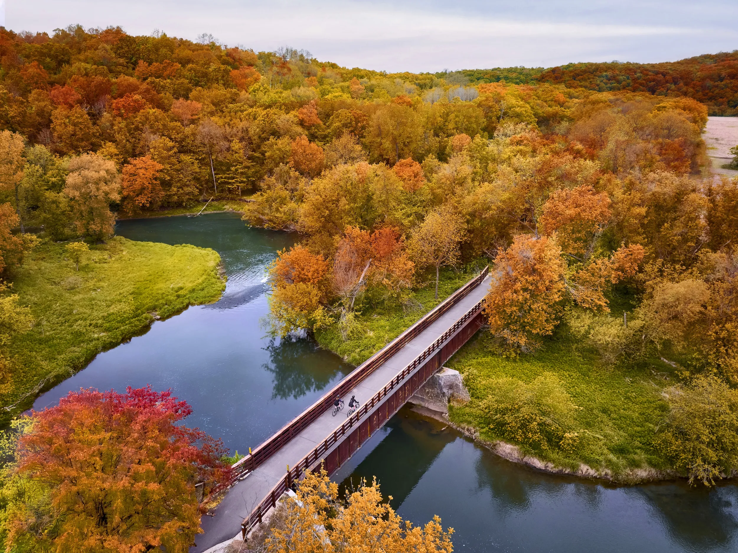 A couple bikers along a bridge in Lanesboro during fall