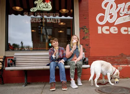 Two kids and dog eating ice cream on bench in Stillwater