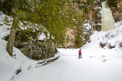 Man snowshoeing next to a frozen waterfall