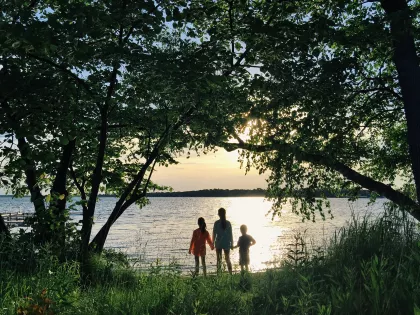 Three children looking out over the water at sunset