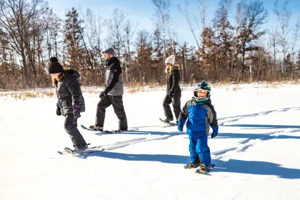A family snowshoeing in the woods near Boyd Lodge