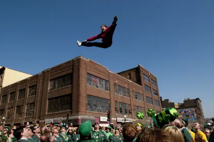 A man doing a split high above onlookers during the St. Patrick's Day Parade in St. Paul