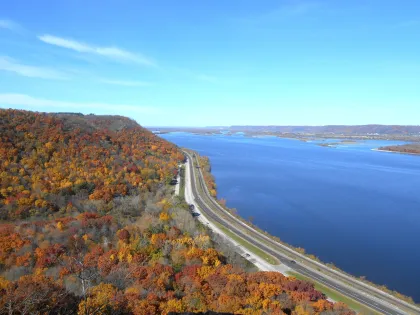 aerial view of curved highway with fall color on left and river on right