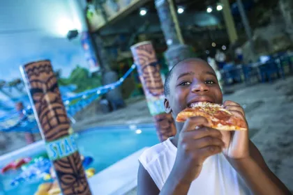 A kid eats pizza at Edgewater Hotel &amp; Waterpark