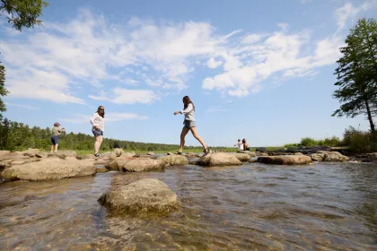 Two women walk across the Mississippi River Headwaters at Itasca State Park