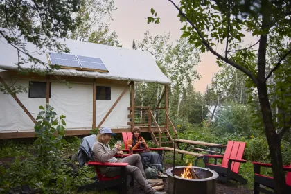 A couple sits by a campfire at North Shore Camping Co in Beaver Bay