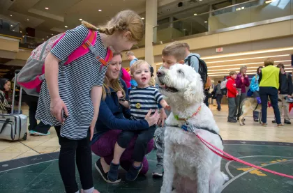An animal ambassador greets a family at MSP Airport