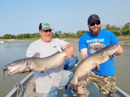 A couple fishermen hold up freshly caught Red River catfish