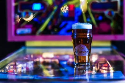 A Bad Weather Brewing pint on top of a pinball machine