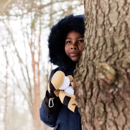 A little boy holds snowballs in his Chopper Mill mittens